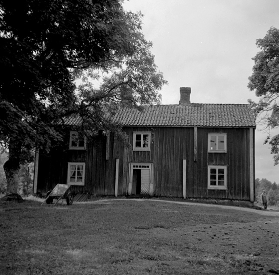Foto på ett bostadshus med en skottkärra framför.