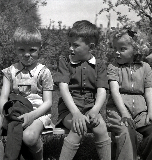 A-K Bergstrands kindergarten, 1942. 
Närbild av tre barn i en trädgård.