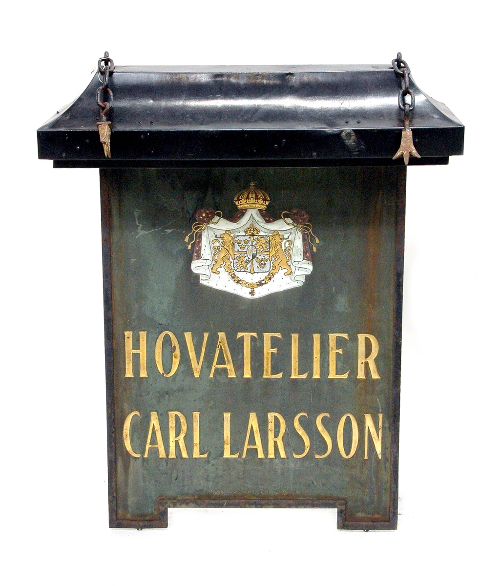 Skylt med väggfäste som har hängt utanför porten på Nygatan 34 i Gävle där firma hovfotograf Carl Larsson hade ateljé 1893-2003.

På den dubbelsidiga skylten finns riksvapnet och texten "HOVATELIER CARL LARSSON".