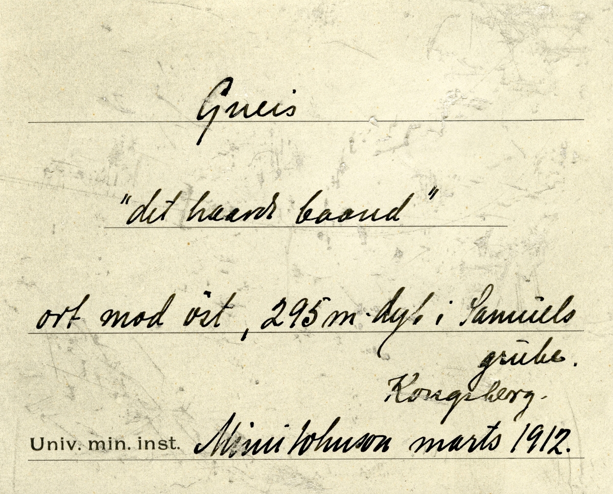 Etikett i eske:

Gneis
«det haarde baand»
ort mod øst, 295 m. dyb i Samuels grube.
Kongsberg.
Mimi Johnson marts 1912.

+ papirlapp