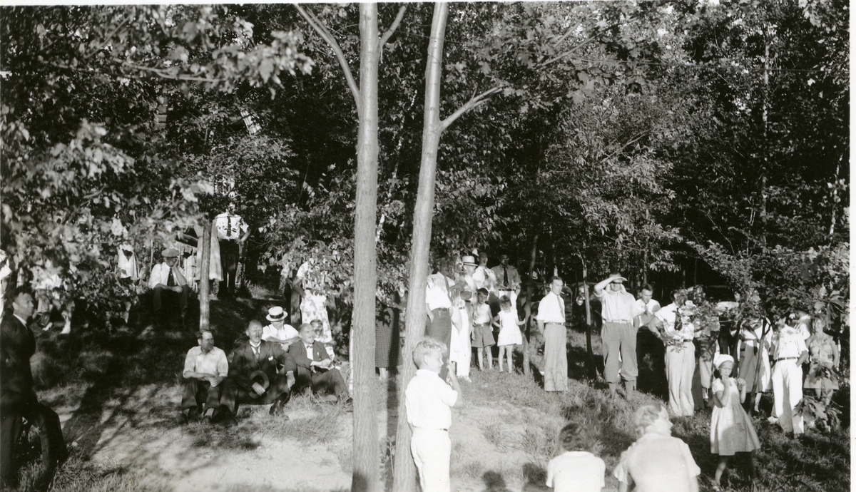 Olaus Islandsmoen sitter til venstre i bildet, med hatt i hånda. Han sitter i en park og det er mange kvinner, menn og barn der. Kan de være tilhørere på et stevne? Dette er i Amerika i 1934.