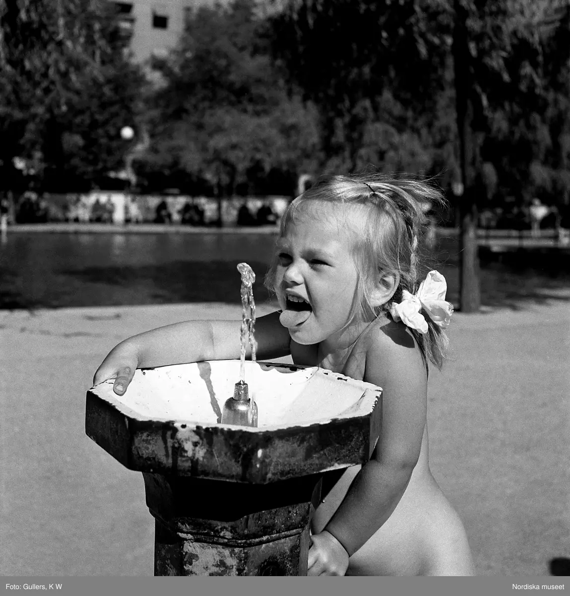 En flicka dricker fr&aring;n en vattenpost