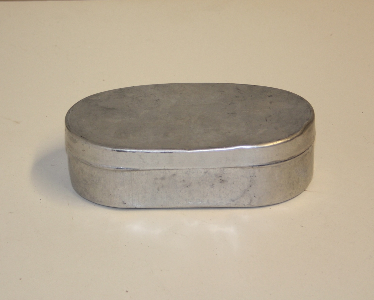 Oval aluminiumsboks med innhold. Innhold er plastslange, 2x tråd, 2x klemmer til til navlestreng, glass sylinder, 2x beholdere med medisin (Sol. nitr. arg. og Nervinal "afi").