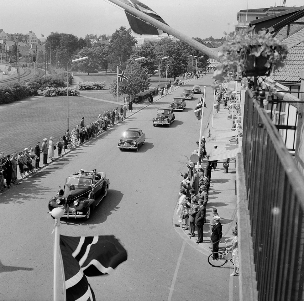 Hamar kommune, Strandgata, signingsreisen 16.06.1958, Kong Olav V og  prinsesse Astrid kjører i åpen bil Buick 1939 modell C-1,  bilkortesje, tilskuere, norske flagg.