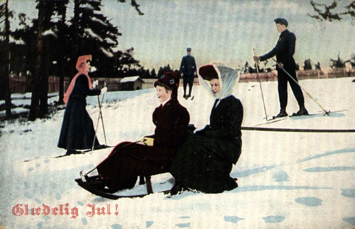 Julekort. Jule- og nyttårshilsen. Vintermotiv. Skiløpere og akere.  Kvinnene i lange skjørt. Stemplet 21.12.1909