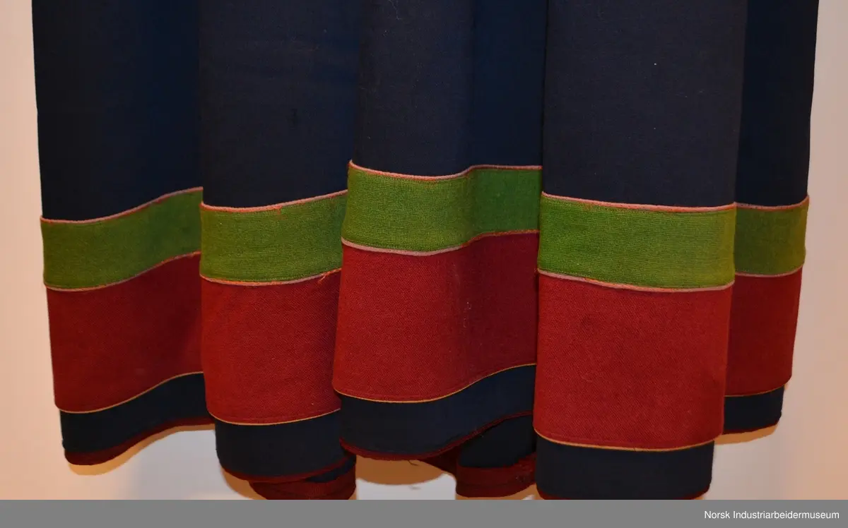 Livet er foret med et ubleket stoff. Livet er mørkt blått med grønn kanting. Både kantene og livet er prydet med plattsøm foran og bak. 
Nederst på stakken er det to border. Den øverste er  i grønt kantet med lilla og orange kontursting. Den nederste er i rødt kantet med gult. Nedenfor bordene ses den mørkeblå stakken. Den er kantet med rødt. 
Det brikkevevde beltet som hører til bunaden er sydd fast i kanten på livet. Borden i midten er orange og svart. På hver ytterside er det en rød, hvit og svart bord. Beltet har også striper i brunt, hvitt, rødt, svart og turkis. Beltet lukkes med hekter. Begge frynseendene på beltet er klipt av. Det ene frynesstykket er montert på beltet, slik at det alltid henger ned langs stakken i samme lengde. Det andre frynsestykket er løst og må festet på beltet med en sikkerhetsnæl eller liknende.