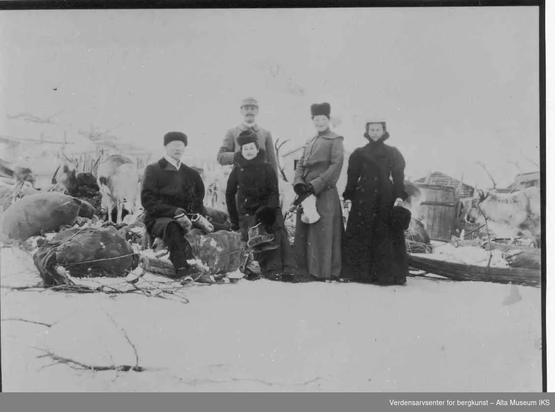 Bossekopmarkedet. 5 vinterkledde personer, deriblant en politimann. Tre kvinner og to menn. Pulker, reinsdyr, tønne