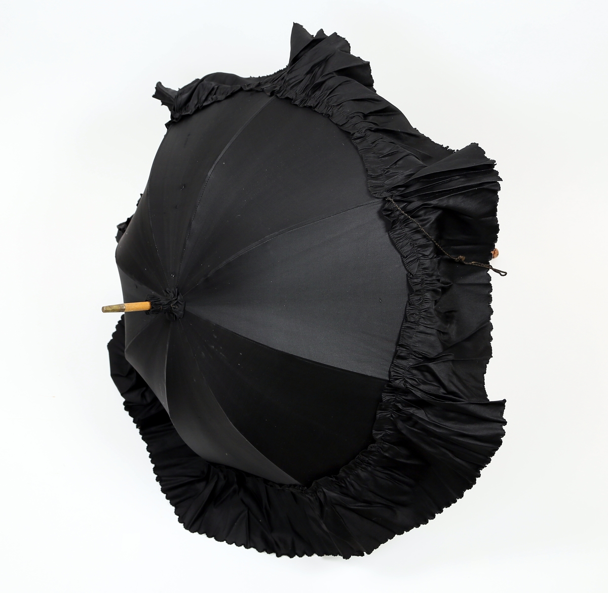 Paraply eller parasoll av tre med utskåret håndtak og kypertvevd svart stoff med en rynkekant ytterst