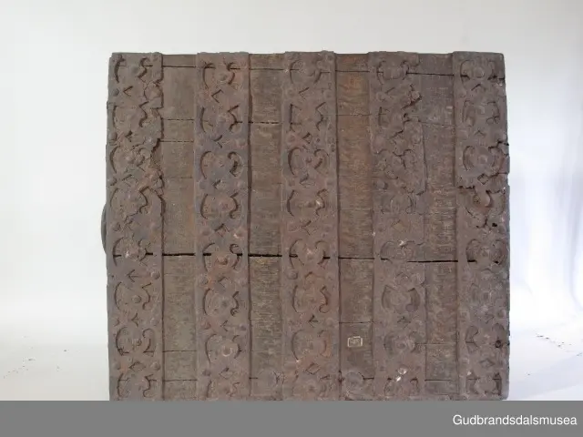 "Rik gjenombroten jarning over heile skrinet. Gamal type, alder uviss. Fra Vestre Gausdal". (Jf. "Katalog for Lom Bygdesamling,1925"). 
Skrinet har 3 rom, nøkkelhullslås og jernhandtak på sidene. Lokket er satt sammen av 2 bord, er festet til utsiden på bakstykket med to hengselbeslag og har 2 sidelister festet med trenagler. Bunnen er satt sammen av 2 bord, festet til hverandre med 2 forsenka trenagler; bunnen er festet til skrinrammen med trenagler.  Skrinrammen er tappet og forsterket med hjørnekantbeslag utvendig. 
Skrinet har jernbeslag med gjennombrutt mønster, 5 stk. B: 6,5 x L: 45 cm på lokk, 3 på hhv. bakstykke, front og sidestykker B: 6,5 x 20 cm. Lokket har ett låsbeslag og de to øvre hengselbeslag festet på innsiden, de to nedre hengselbeslag er festet på utsiden av bakstykket. Alle beslag er festet med store jernnagler samt festet under bunn på skrinet. De to hengselbeslag har også gjennombrutt mønster.  Nøkkelhullslåsen mangler låsanordning på innsiden.
DEKOR. Malingen har blitt beskyttet med et lag ferniss el.l., noe som ble vanlig fra begynnelsen av 1700-tallet. Ingen skurddekor. I stedet er beslag av jern brukt som dekorelement, noe som periodemessig kan peke på 1600-tallet, tidlig 1700-tallet, der treskurden ikke var fremherskende. Liknende dekorbruk finner du på LBY0328. Skrinet har gjennombrutt mønster på beslag og store jernnagler som beslagfeste. Treverket som synes mellom beslagene er malt med horisontale bølgestrukturer i gul og brun. Den dominerende dekorfargen er brun og gul, men det finnes små rester av blå eller blågrønn på lokk, sidelister på lokk, front og bunnkant på bakstykket samt av gul på frontbeslag. Innsiden av lokket er malt i terracottarød nyanse. Tradisjonelt fremkom denne fargen ved bruk av saft fra orr blandet med spytt, som ble smurt ut over treet. 
BRUK. Før kofferten kom i bruk hadde man reiseskrinet, som ble brukt til oppbevaring av bl.a. klær, verdisaker og mat på reiser. Skrinet hadde ofte et eller to mindre, smale rom langs den ene skrinsiden og ett større rom. De fleste reiseskrin var i tillegg forsterket med jernbeslag langs alle kanter og med en solid nøkkelhullås til sikring mot støt, slag og tyveri.