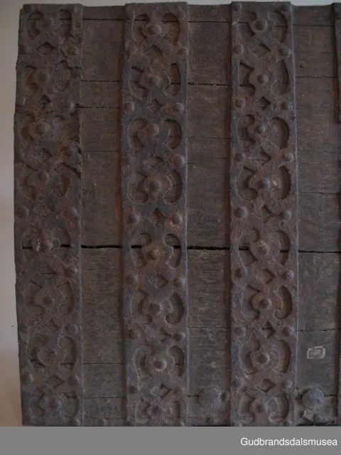 "Rik gjenombroten jarning over heile skrinet. Gamal type, alder uviss. Fra Vestre Gausdal". (Jf. "Katalog for Lom Bygdesamling,1925"). 
Skrinet har 3 rom, nøkkelhullslås og jernhandtak på sidene. Lokket er satt sammen av 2 bord, er festet til utsiden på bakstykket med to hengselbeslag og har 2 sidelister festet med trenagler. Bunnen er satt sammen av 2 bord, festet til hverandre med 2 forsenka trenagler; bunnen er festet til skrinrammen med trenagler.  Skrinrammen er tappet og forsterket med hjørnekantbeslag utvendig. 
Skrinet har jernbeslag med gjennombrutt mønster, 5 stk. B: 6,5 x L: 45 cm på lokk, 3 på hhv. bakstykke, front og sidestykker B: 6,5 x 20 cm. Lokket har ett låsbeslag og de to øvre hengselbeslag festet på innsiden, de to nedre hengselbeslag er festet på utsiden av bakstykket. Alle beslag er festet med store jernnagler samt festet under bunn på skrinet. De to hengselbeslag har også gjennombrutt mønster.  Nøkkelhullslåsen mangler låsanordning på innsiden.
DEKOR. Malingen har blitt beskyttet med et lag ferniss el.l., noe som ble vanlig fra begynnelsen av 1700-tallet. Ingen skurddekor. I stedet er beslag av jern brukt som dekorelement, noe som periodemessig kan peke på 1600-tallet, tidlig 1700-tallet, der treskurden ikke var fremherskende. Liknende dekorbruk finner du på LBY0328. Skrinet har gjennombrutt mønster på beslag og store jernnagler som beslagfeste. Treverket som synes mellom beslagene er malt med horisontale bølgestrukturer i gul og brun. Den dominerende dekorfargen er brun og gul, men det finnes små rester av blå eller blågrønn på lokk, sidelister på lokk, front og bunnkant på bakstykket samt av gul på frontbeslag. Innsiden av lokket er malt i terracottarød nyanse. Tradisjonelt fremkom denne fargen ved bruk av saft fra orr blandet med spytt, som ble smurt ut over treet. 
BRUK. Før kofferten kom i bruk hadde man reiseskrinet, som ble brukt til oppbevaring av bl.a. klær, verdisaker og mat på reiser. Skrinet hadde ofte et eller to mindre, smale rom langs den ene skrinsiden og ett større rom. De fleste reiseskrin var i tillegg forsterket med jernbeslag langs alle kanter og med en solid nøkkelhullås til sikring mot støt, slag og tyveri.