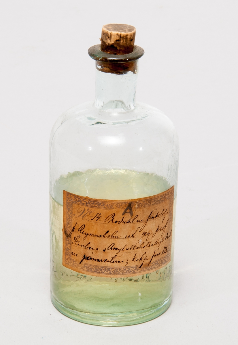 Prov på produkt ur finkelolja, i  flaska av glas med etikett: "No 14. Produkt ur finkelolja fr Reymersholm […] prof Stenberg. Amylakoholhaltig […]; kokp. före 133 gr."