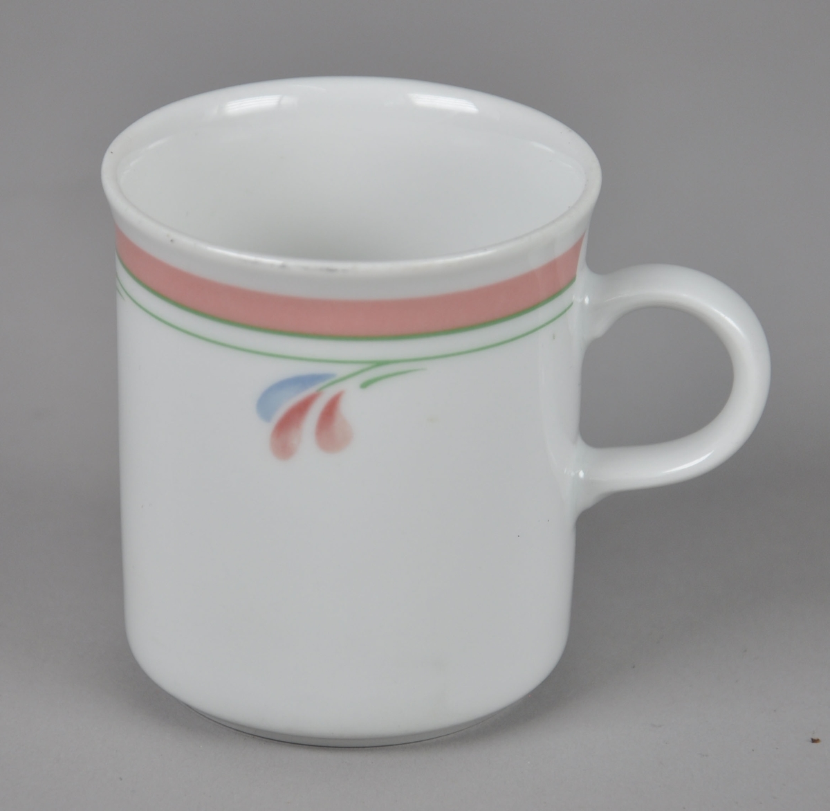 Kaffekopp av glassert keramikk, med hank. Koppen har malt dekor på utsiden med motiv av linjer og blader.