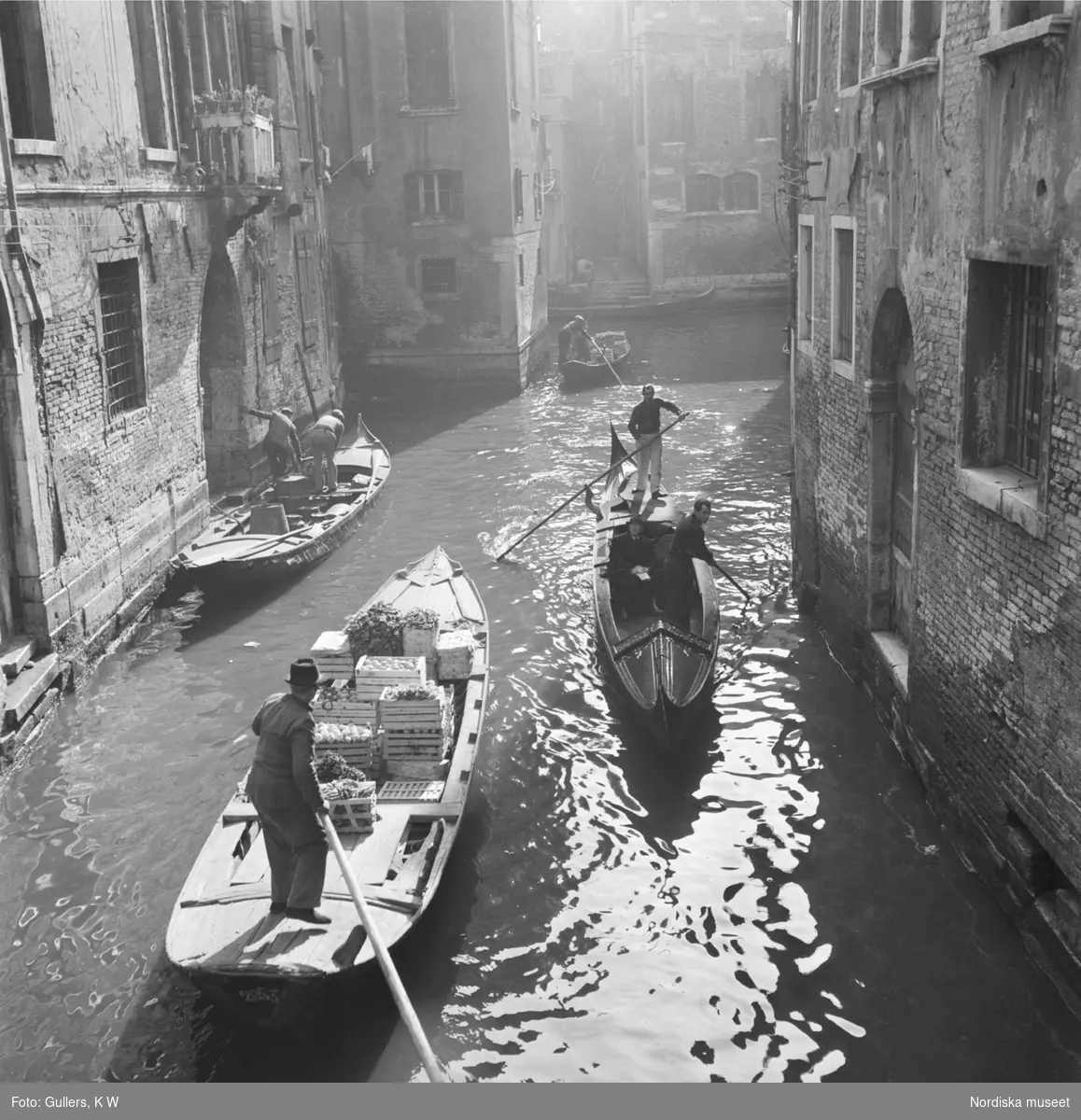 Byggnadsmaterial, grönsaker och människor som forslas med gondoler på Venedigs kanaler