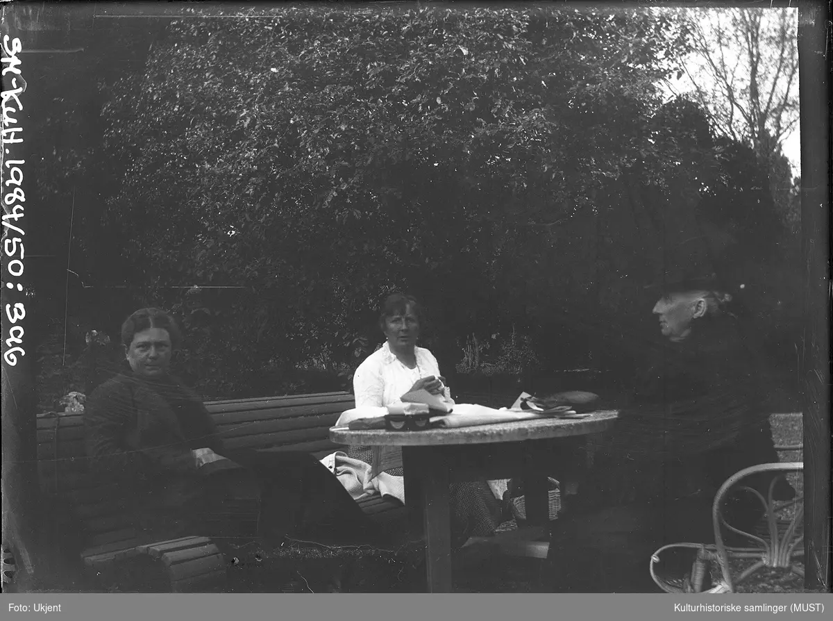 Tre kvinner broderer ved hagebordet på Breidablikk.