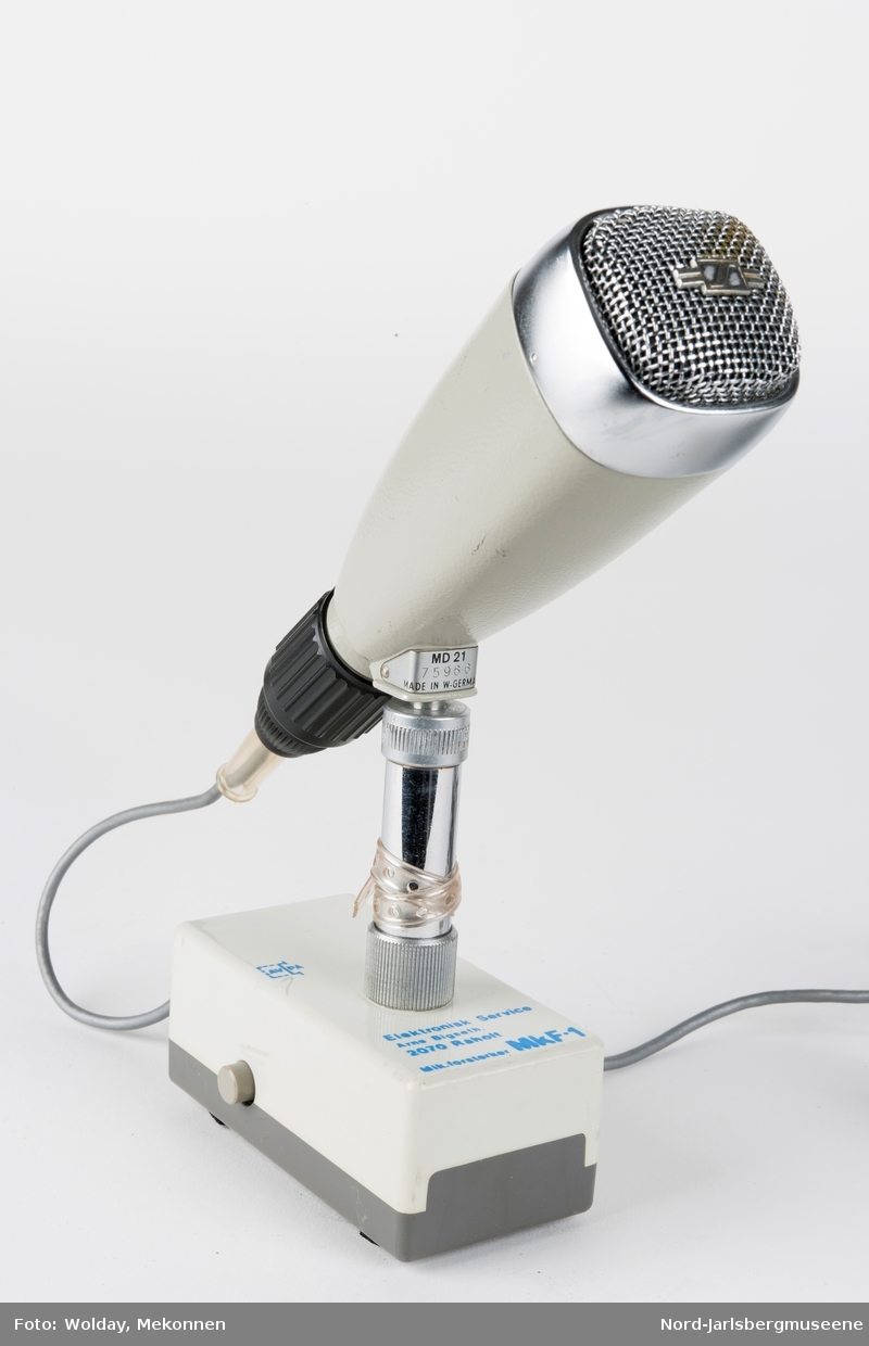 Bordmikrofon montert på en kort stang til en rektangulær fot (forsterker?)med to forskjellige el-kobling til headset?
Selve mikrofonen er kantet konisk med lydhode i blan
kt metall.