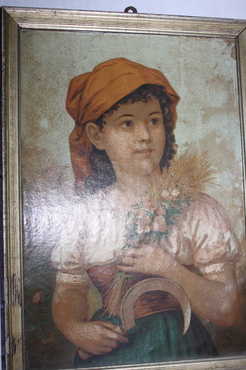 Flicka klädd i vit blus med rött livstycke och blågrön kjol. På huvudet ett rött huckle. I vänster hand håller hon en bukett bestående av blommor och sädesax. I höger hand håller hon en skära.