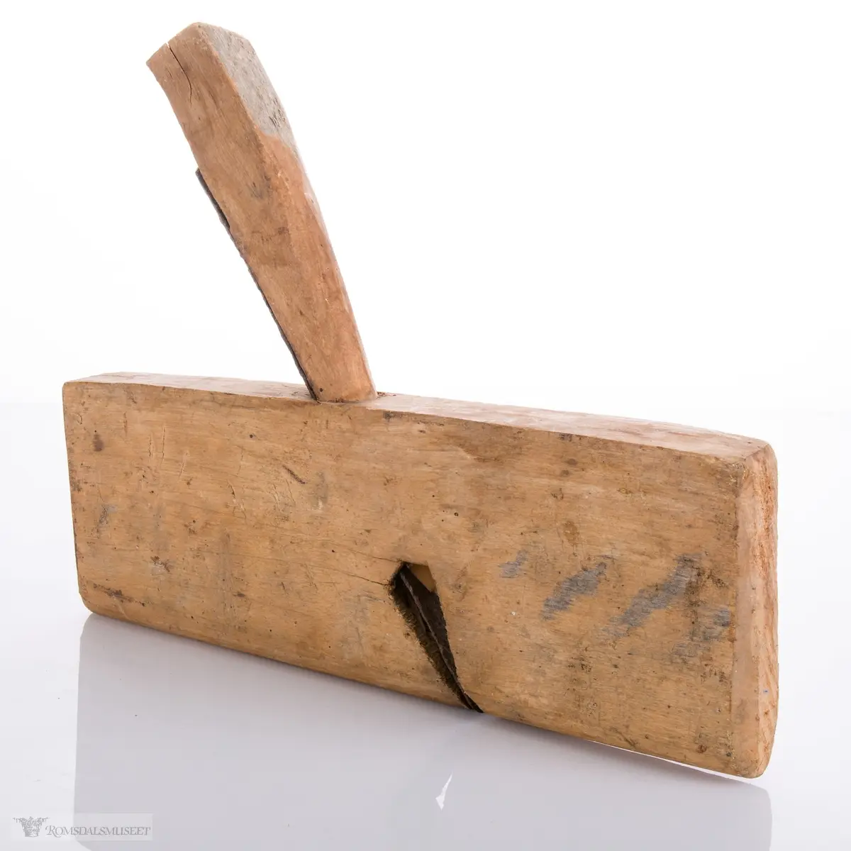 Enkel høvel skåret ut av et stykke tre som er avrundet under. Langt avrundet jern og utskåret kile.