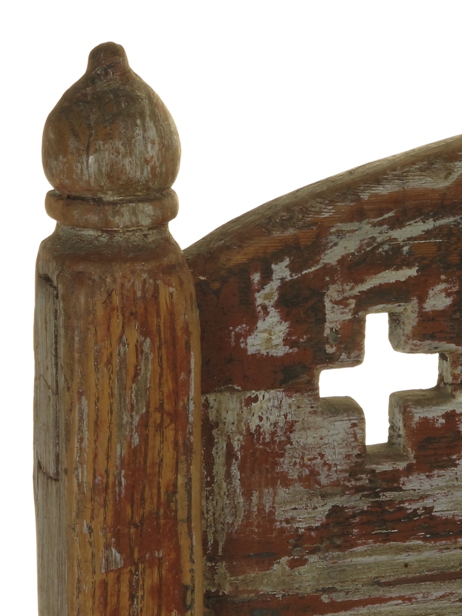 Senmiddelaldersk type, av dreiede pinner. Muligens opprinnelig kirkestol, da der er rader med kors i ryggen. Armlenene har på undersiden festet 6 små  balustre, som nedentil er festet i nok en dreiet tverrligger. Der har likeledes vært balustre (3 stk) under sargen i fronten ned til den øvre tverrstreber. Ryggen består av avvekslende dreiede balustre i tett  rad og horisontale bretter med utskårne gjennombrutte kors. Buet toppstykke. Endene av bakstavene har dreide knotter.