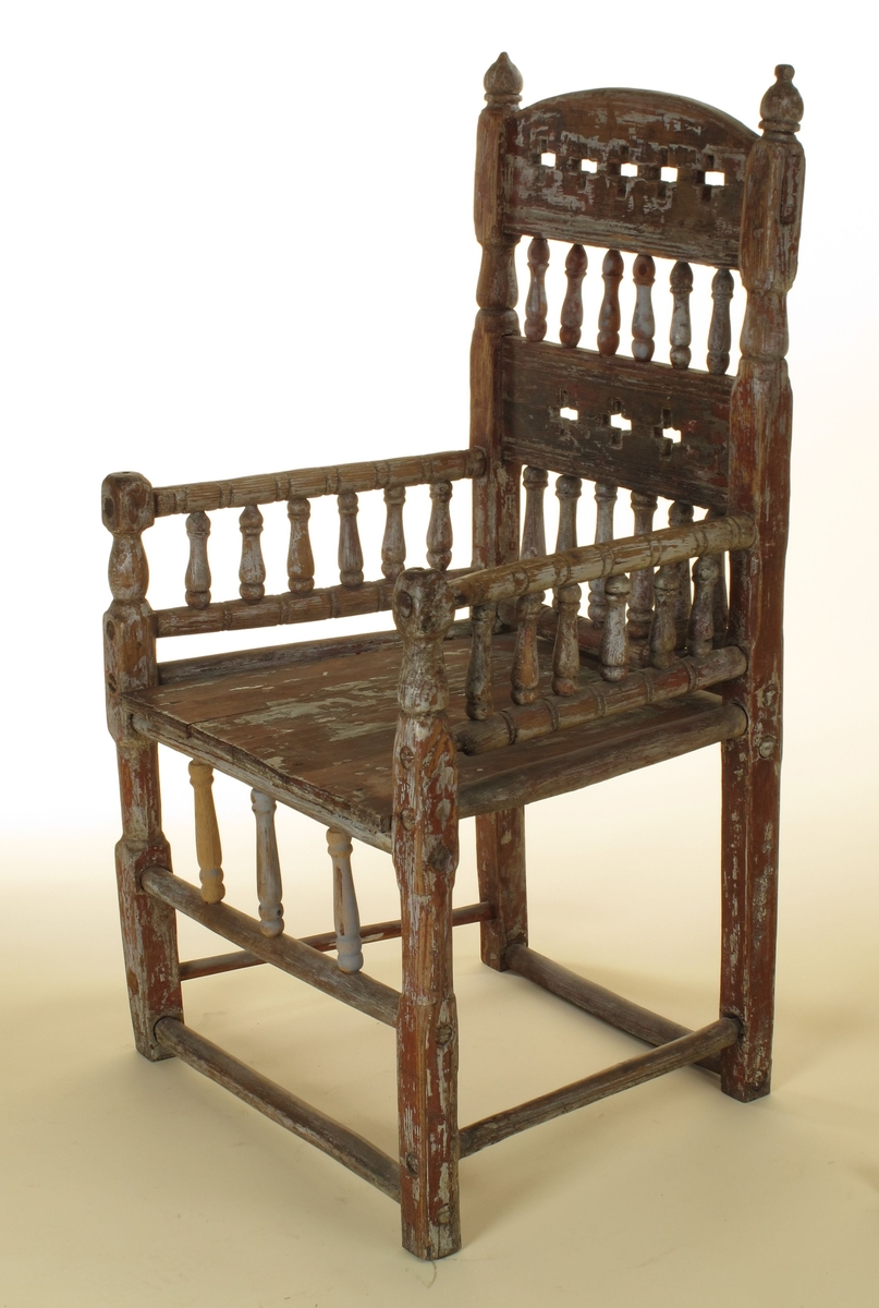 Senmiddelaldersk type, av dreiede pinner. Muligens opprinnelig kirkestol, da der er rader med kors i ryggen. Armlenene har på undersiden festet 6 små  balustre, som nedentil er festet i nok en dreiet tverrligger. Der har likeledes vært balustre (3 stk) under sargen i fronten ned til den øvre tverrstreber. Ryggen består av avvekslende dreiede balustre i tett  rad og horisontale bretter med utskårne gjennombrutte kors. Buet toppstykke. Endene av bakstavene har dreide knotter.