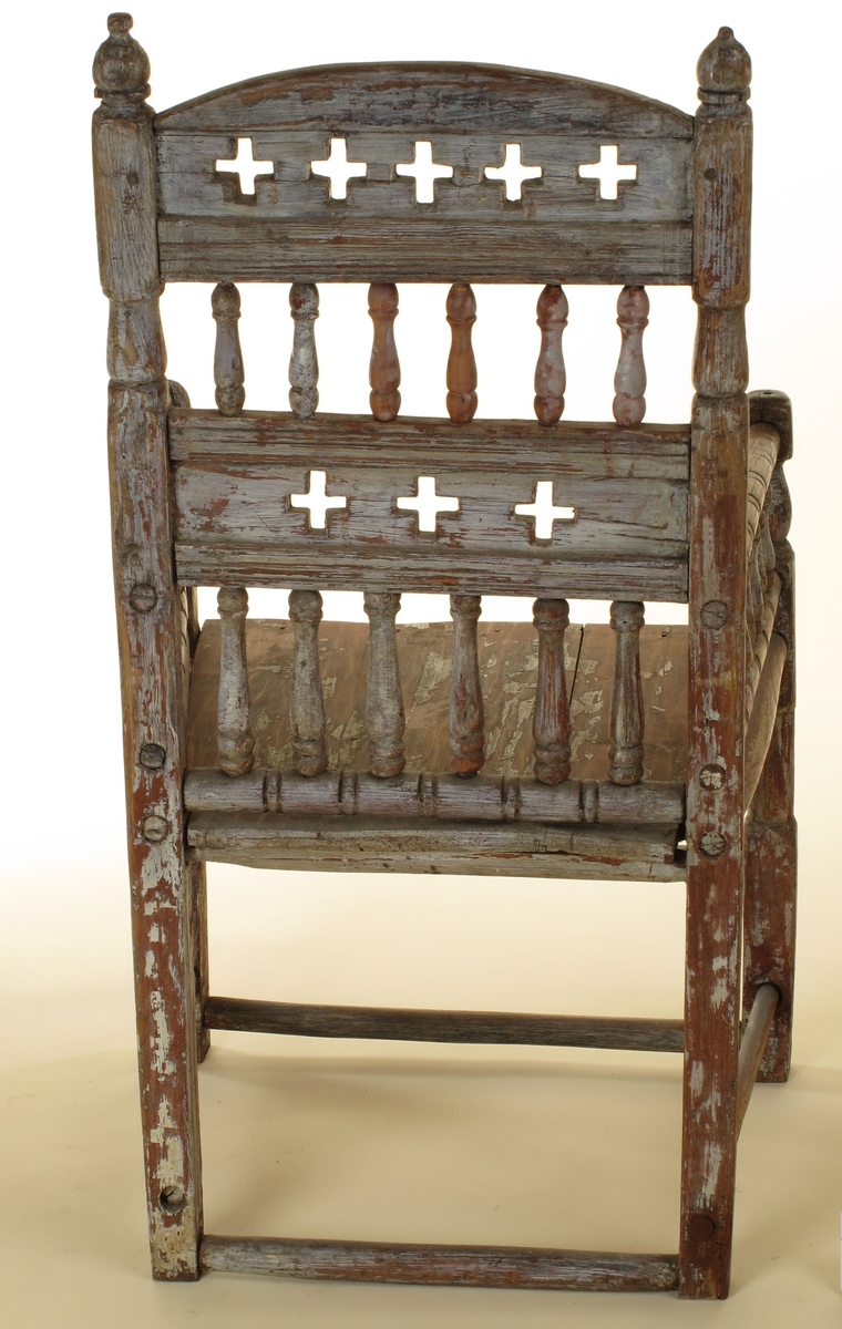 Senmiddelaldersk type, av dreiede pinner. Muligens opprinnelig kirkestol, da der er rader med kors i ryggen. Armlenene har på undersiden festet 6 små  balustre, som nedentil er festet i nok en dreiet tverrligger. Der har likeledes vært balustre (3 stk) under sargen i fronten ned til den øvre tverrstreber. Ryggen består av avvekslende dreiede balustre i tett  rad og horisontale bretter med utskårne gjennombrutte kors. Buet toppstykke. Endene av bakstavene har dreide knotter.