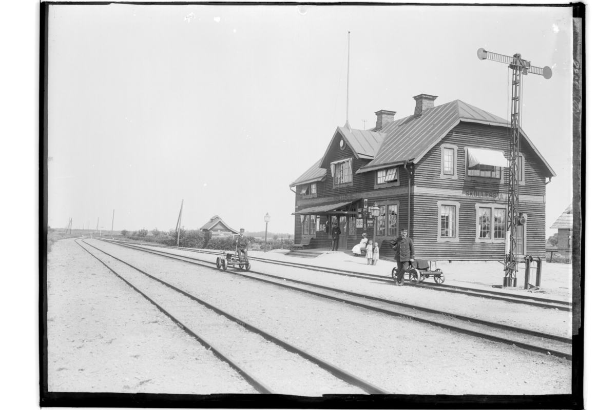 Sköllersta Järnvägsstation, en och en halvvånings stationsbyggnad med brutet tak.Två dresiner med två män.