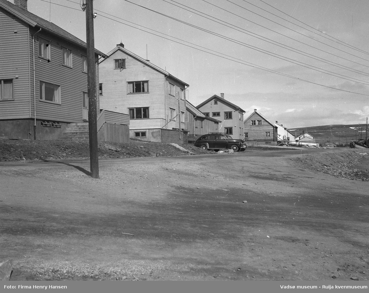 Oscarsgata i Vadsø sett fra vest mot øst.  Den hvite bygningen, nr to i bildet med en sort personbil parkert foran, antas å være Niskagården. Gaten som går mellom bygning fire og fem er Kirkegata. Bygning nummer fem er muligens Bettenhuset. Bildet er tatt 17 mai 1951.