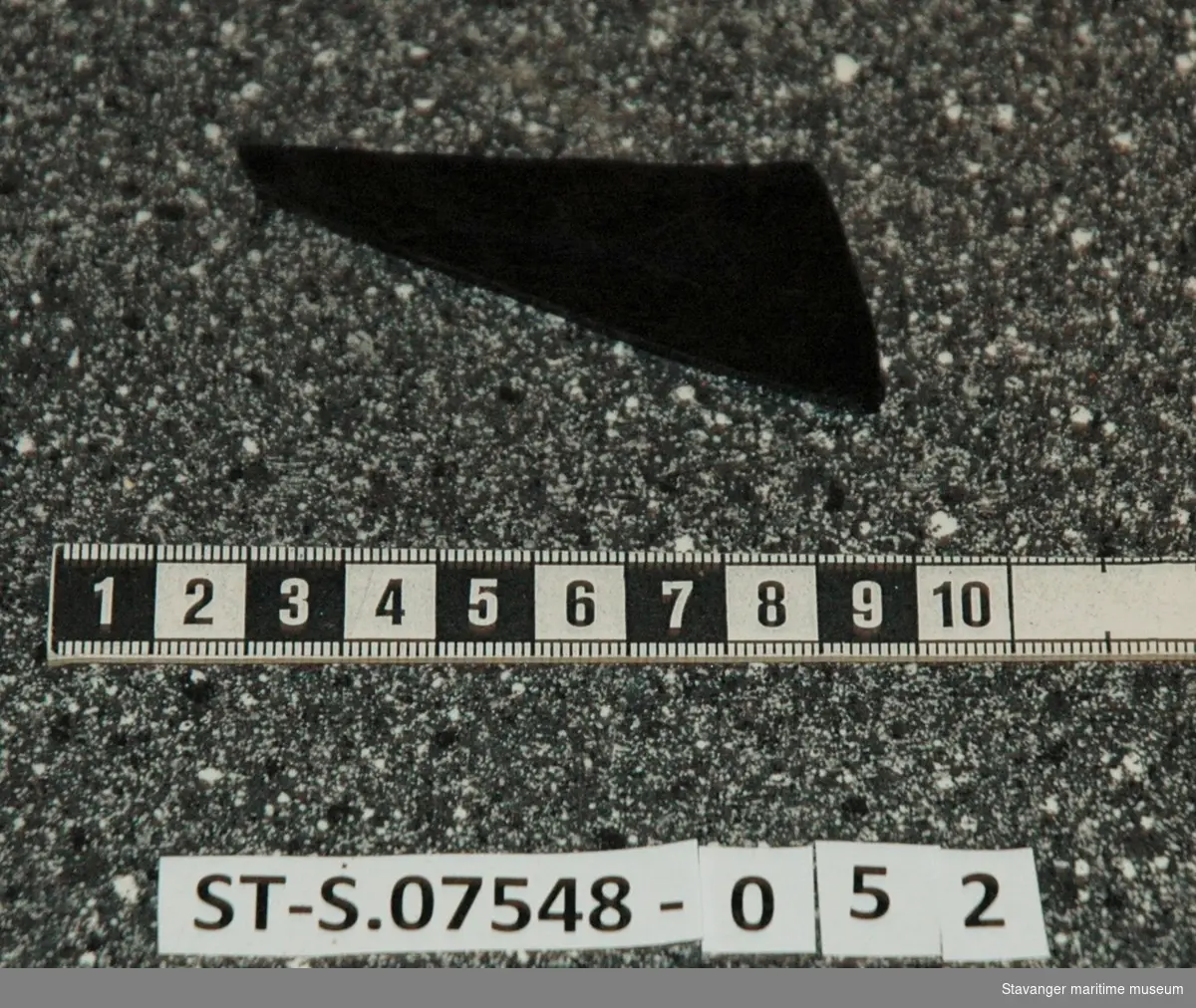 Uvisst fragment av utformet materiale, mulig mørkt glass