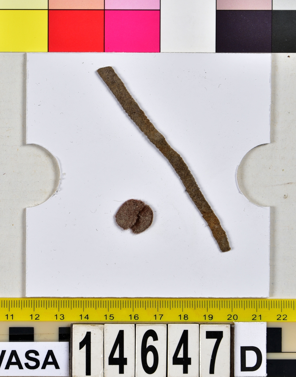 Textil.
8 textilfragment uppdelat på fyndnummer 14647a-e.
Fnr 14647a består av ett fragment av ull vävt i tuskaft.
Fnr 14647b består av två fragment av ull vävda i tuskaft.
Fnr 14647c består av en del av en fåll av silke.
Fnr 14647d består av tre fragment av ull. Det ena är ett vävt band och de andra fragmenten är två halvor av textil som tillsammans bildar en liten rund plätt.
Fnr 14647e är en tygbit med blommönster. "Materialet är svart ull och ljust silke. Det är en ovanlig typ av tuskaftsvävnad med mönsterinslag som ligger obundet mellan tuskaftsinslagen. Mönsterinslagen bildar ett blommönster inom varje rapport som har typisk 1600-talskaraktär. Tillskärning och fållar finns längs alla fyra sidorna. Det är omöjligt att bestämma vad det ursprungligen har varit. Storlek och form anger att det bör ha tillhört något klädesplagg." Looström och Stapf, Tre tusen textilfragment, 1983, s. 29.
Fnr 14647 innehas också av en nål som hör till fyndet.
