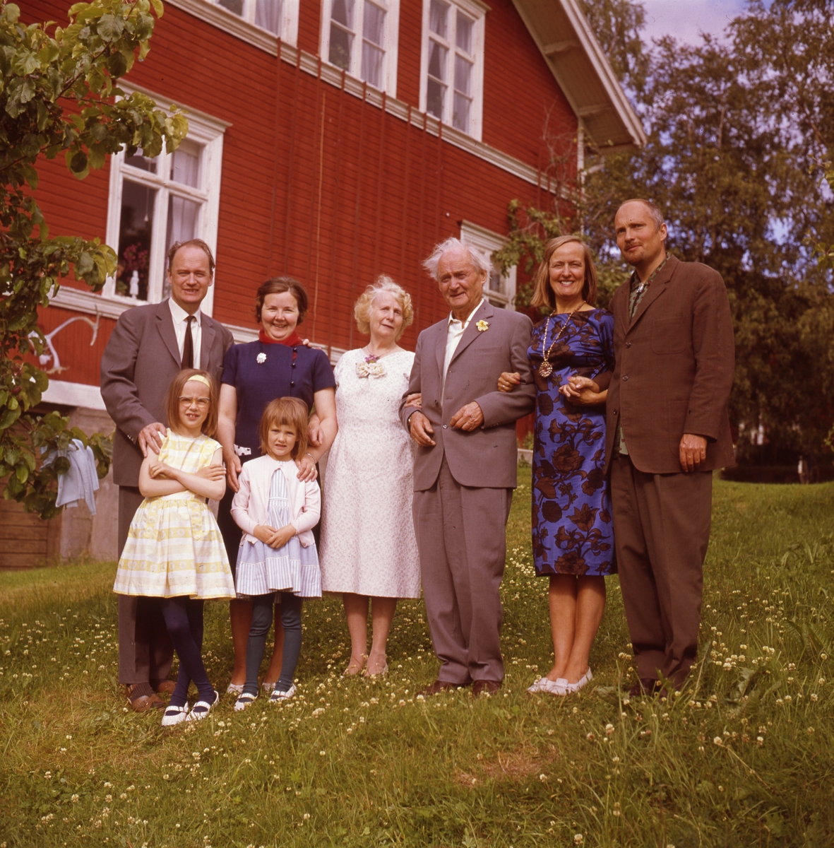 Det är sommar. Framför ett stort, rött trähus står Albert Viksten i armkrok med sin fru  och resten av familjen.