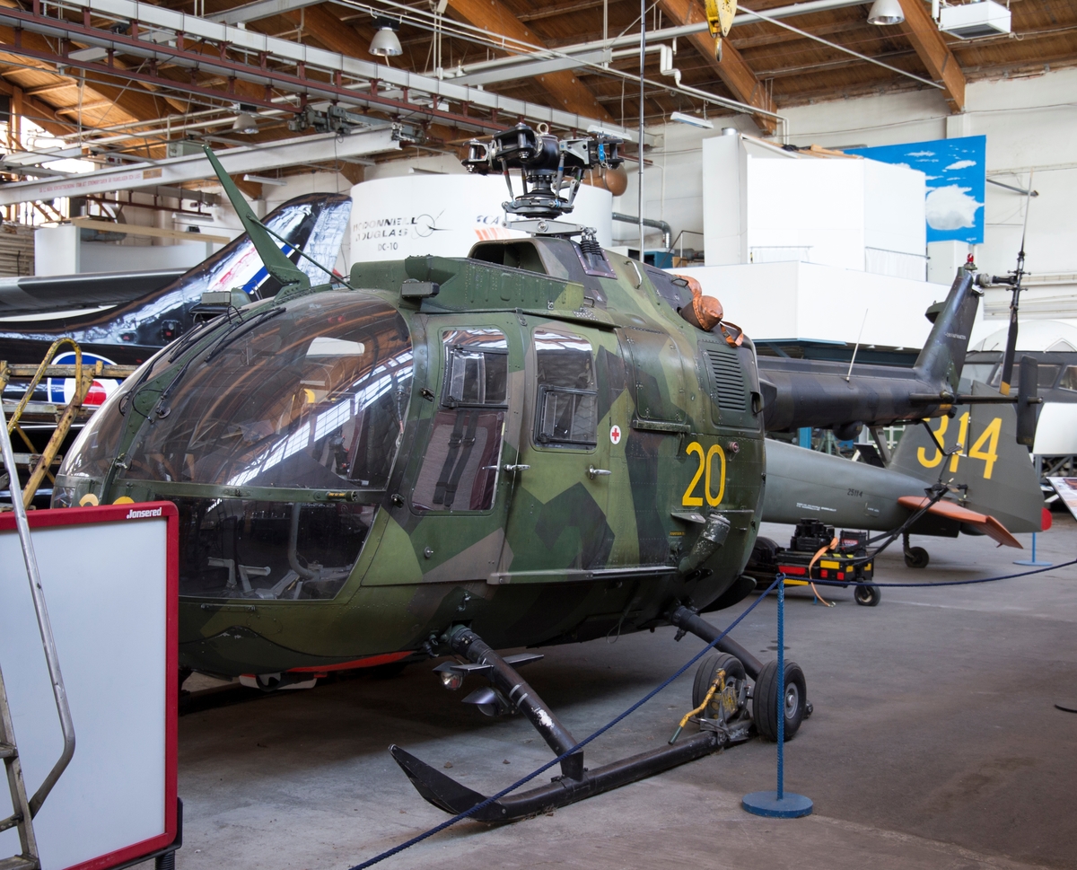 Helikopter, HKP 9A
MBB BO 105 CBS

Kamouflagemålad attackhelikopter utrustad med två turbinmotorer. 
Fyrbladig rotorinstallation på ovansidan samt mindre tvåbladig rotor på fena.
Märkning: Kodsiffra 20 fram och på sidan, kronmärke på bakkroppen samt texten Försvarsmakten bak.