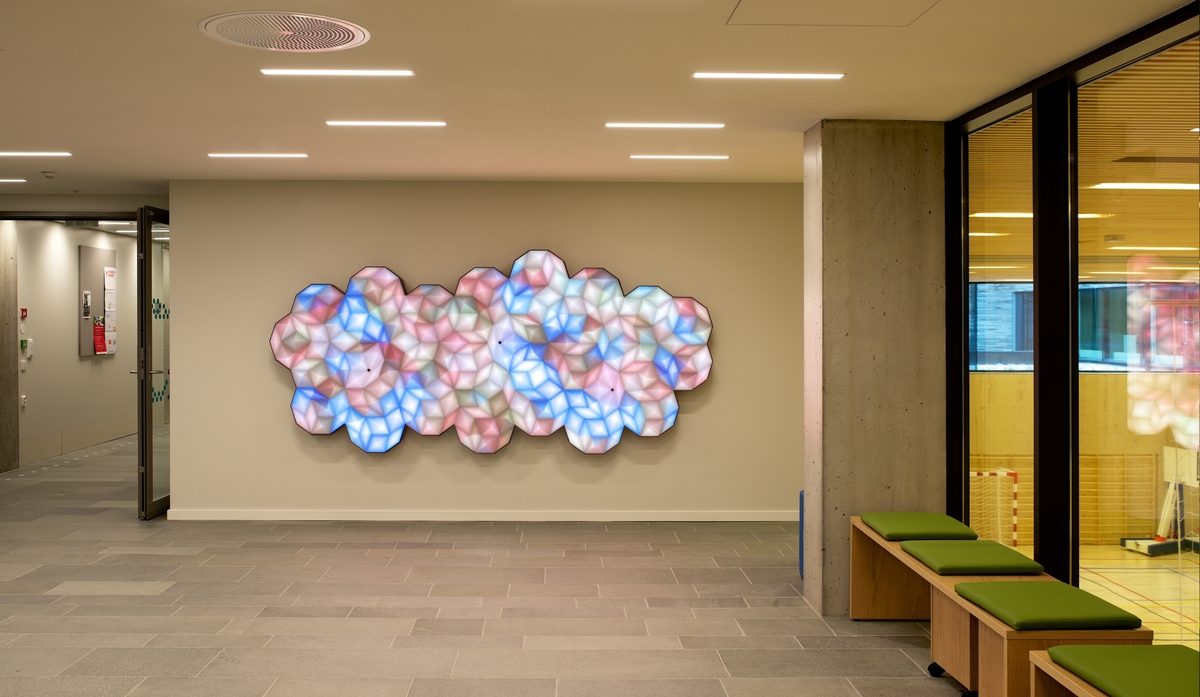 I adkomstrommet skal kunstnerne Miriam Sleeman (UK) og Tom Sloan (AU) lage et lysbasert kunstverk ved navn Colour Clouds. Verket skal bidra til å skape en atmosfære av omsorg og ro i et miljø der mange ellers opplever usikkerhet eller til og med frykt. En stor ledlys-skjerm er dekket av abstrakte fargemønstre som forandres i tråd med dagslyset og sesongenes skiftninger. Fargehjulet er utviklet i samarbeid med sykehuset. Når det er fredelig i lokalet, glir de ulike fargene sakte rundt i vakre mønstre. Når man nærmer seg, vil kunstverket reagere dynamisk. Det røde skjerfet, den gule regnjakken eller bagen man holder i hånden, vil «smitte av» på kunstverket og henge i til man har gått videre, før det rolige mønsteret overtar igjen. Fargeskyene oppmuntrer til å stoppe opp et øyeblikk, undre seg og utforske.