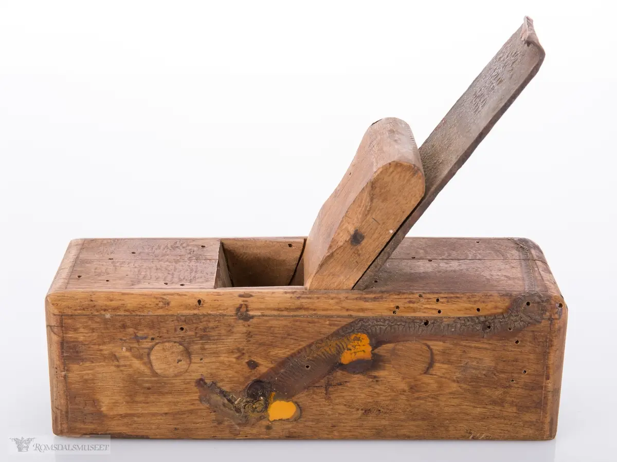 Liten rektangulær høvel med jern og kile. Konkavt u- formet spor i sålen.