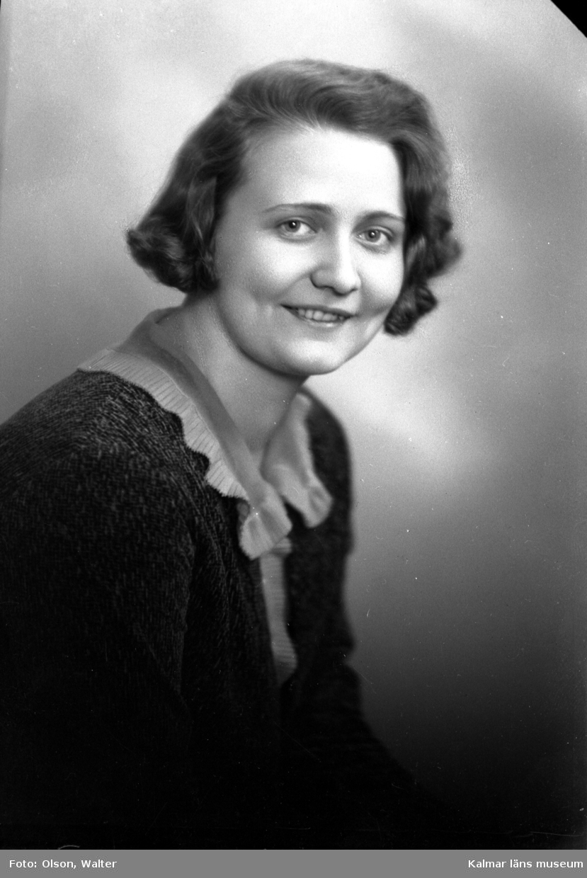 Ateljébild på en kvinna i blus, volangkrage och jacka. Enligt Walter Olsons journal är bilden beställd av Rut Malmrot.