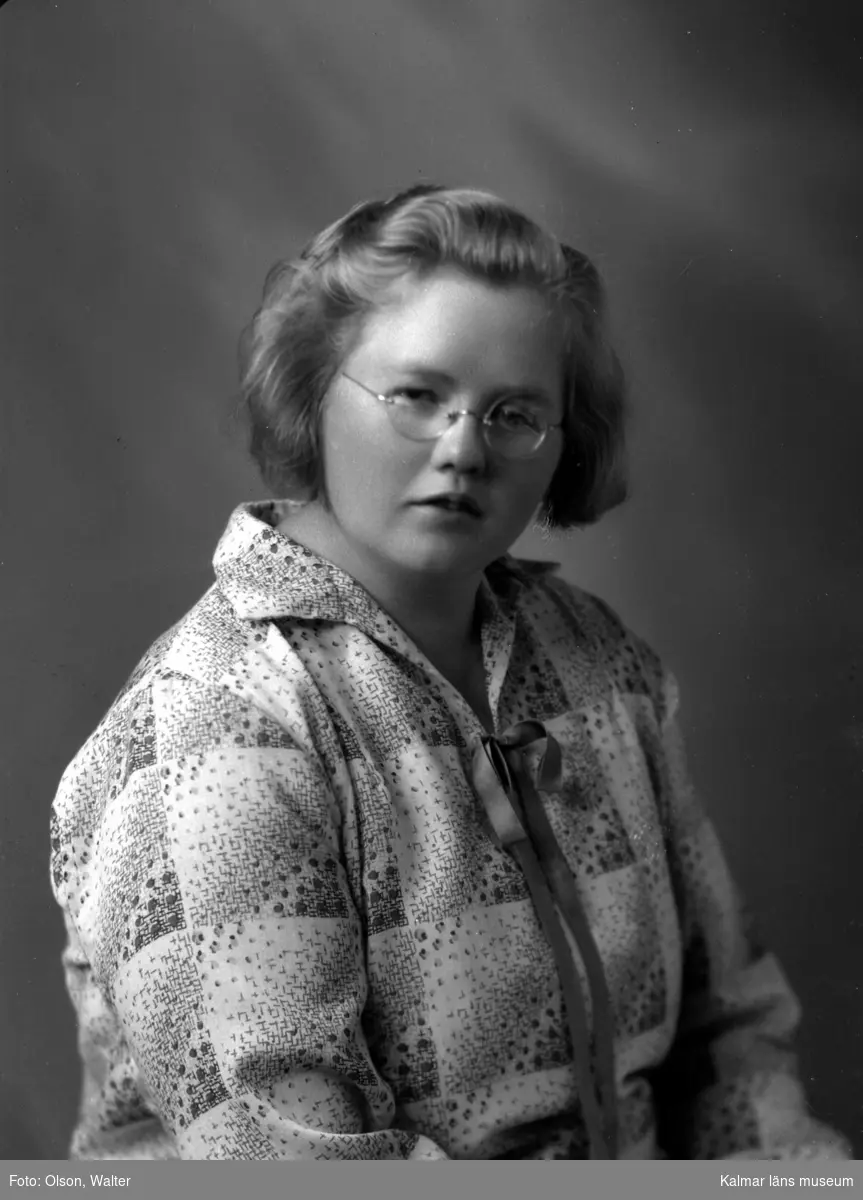 Ateljébild på en kvinna i blus och glasögon. Enligt Walter Olsons journal är bilden beställd av Lisa Sjöström.