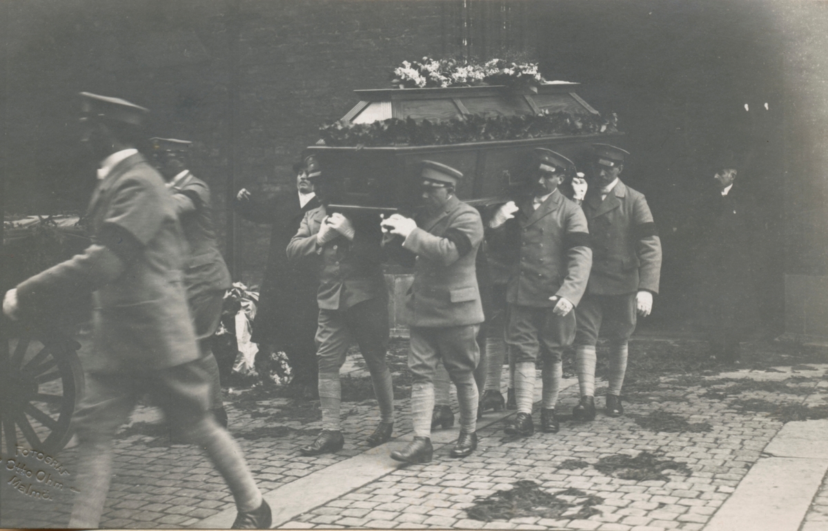 Militärer som bär på en kista vid en begravning.