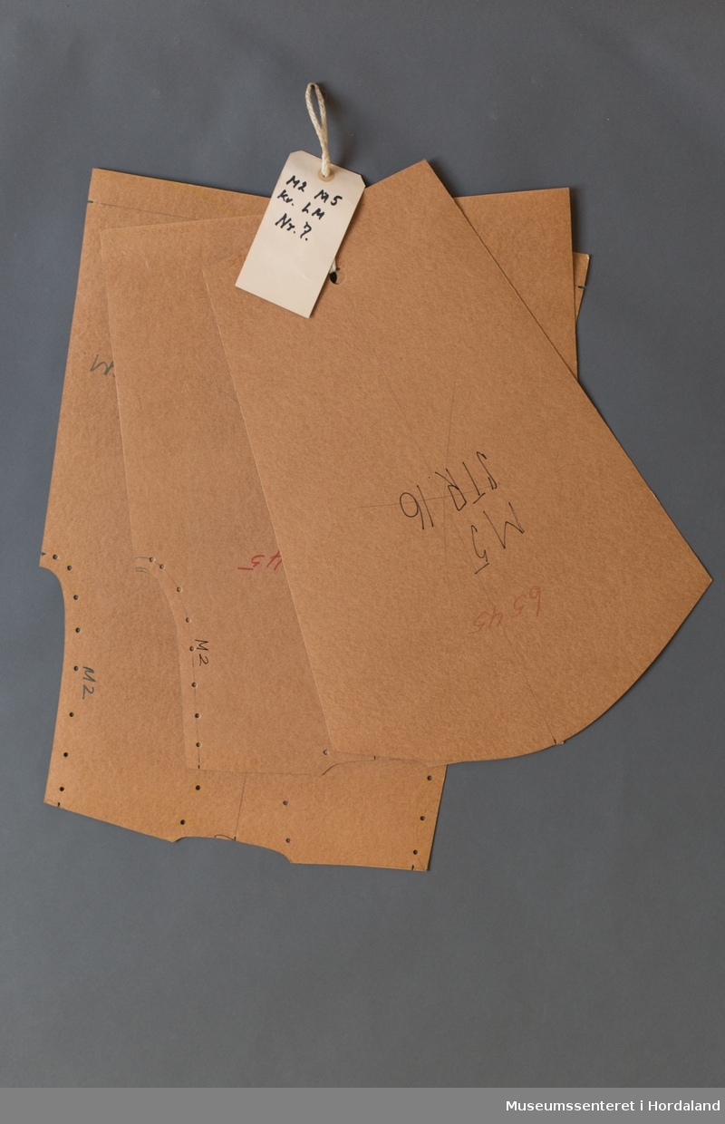 Mønsterskantar i papp, brukt til å skjere ut ulike delar av plagg i klesproduksjon. Desse er til ein genser, M2 M5, kvalitet LM, nr. 7.
