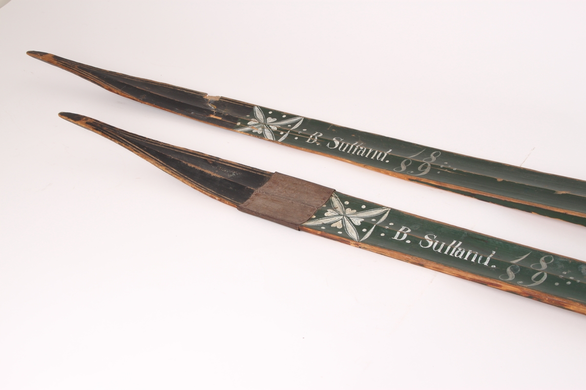 Et par treski i helved med lang og smal tupp, flat overside og fortykning under. Avsmalnende framski og jevnbred bakski og møneformet rygg langs hele skiens lengde. Dekoren er fra Krødsherad med fremre del av framskien malt i svart, og med rosett og navn med årstall i hvitt. Rosett også på skienes bakende. Skiene har tåstropp av vidje og har sannsynligvis hatt ilkebinding. Bindingshullene har innskjæring med skråsnitt på skienes sider. Skiene er rett avskåret bak. Ingen rand under.