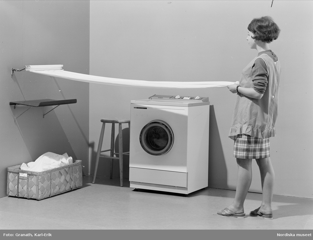 En kvinna drar lakan i en lakansträckare i en tvättstuga.