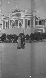 Sommer. En Kvinne og en mann poserer på stranden. Stor bygni