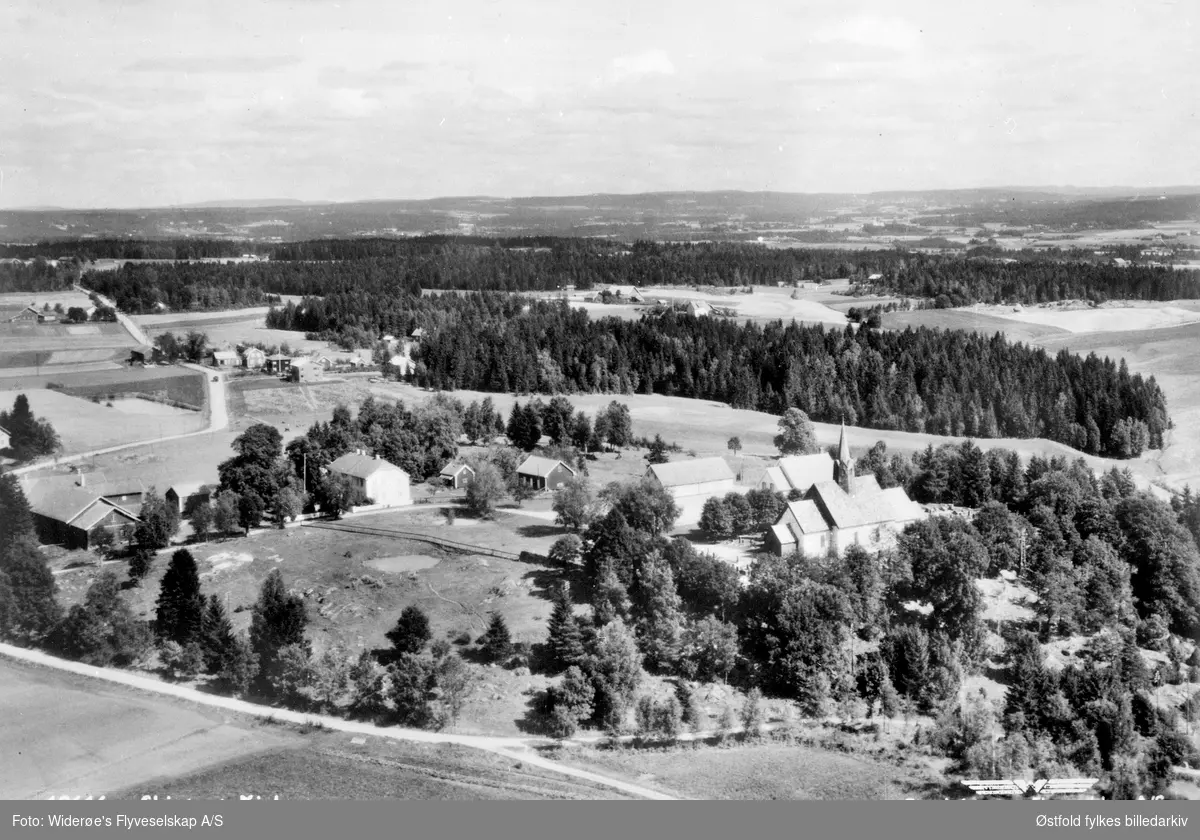 Skråfoto av Skiptvet kirke og prestegård ca. 1950.