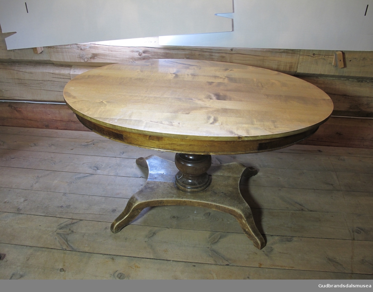 Salongbord, et biedermeierbord. Bordet har oval bordplate over en kraftig dreid stod. Underst er det en mindre plate med fire små bein. Bordet er lakket.