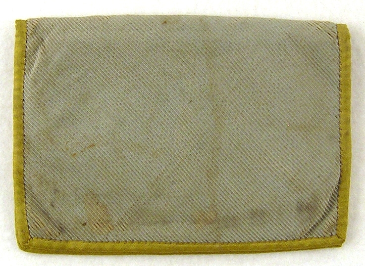 Plånbok av ljust grönblått siden, dubbel, blårött bomullsfoder samt kantad med gult sidenband runtom. I ena facket isydd läderbit med isnkription: Löfvenskiöld Mariestad. Smutsig.