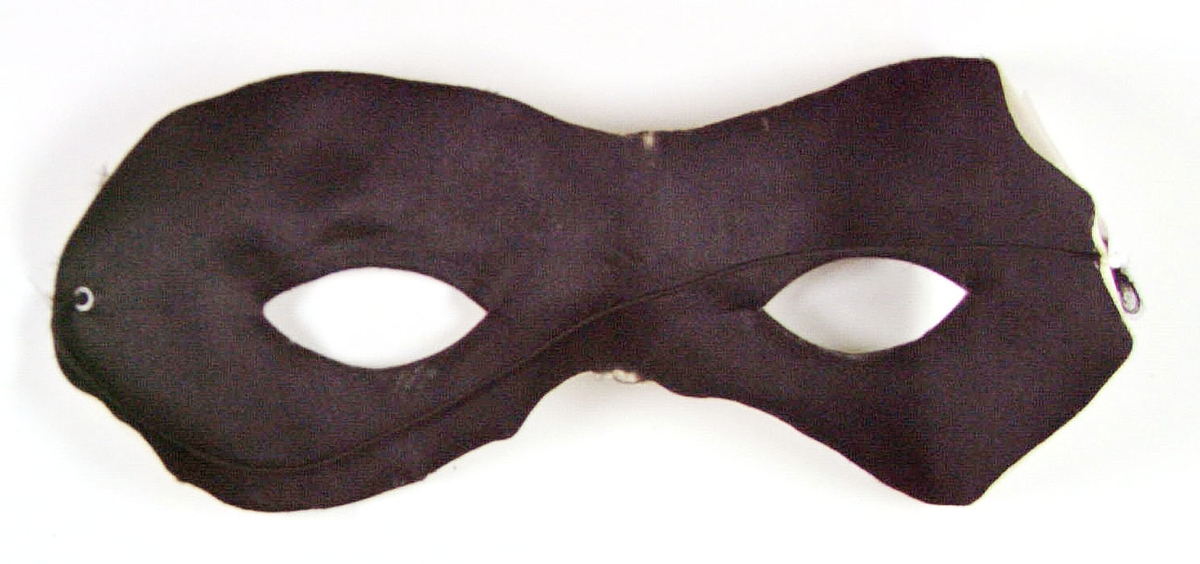 Ansiktsmask av svart tyg uppfodrad på vit, vaxduksliknande stomme. Märkt "Made in Sweden".