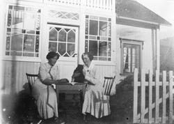 Kvinner, klær, bord og stoler, bolighus.