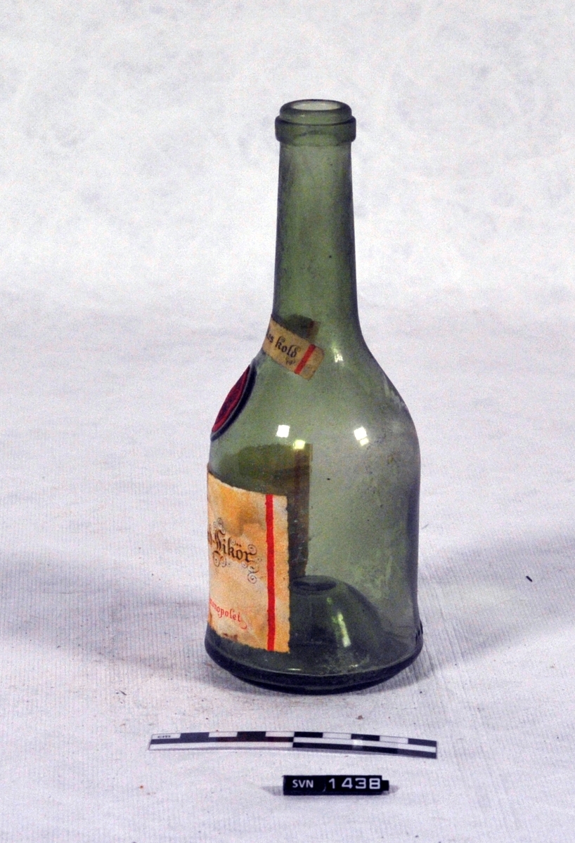 Grønn flaske med lang hals.
Flasken er uten innhold og har ikke kork.
Flasken har to etiketter og en voksmerke.