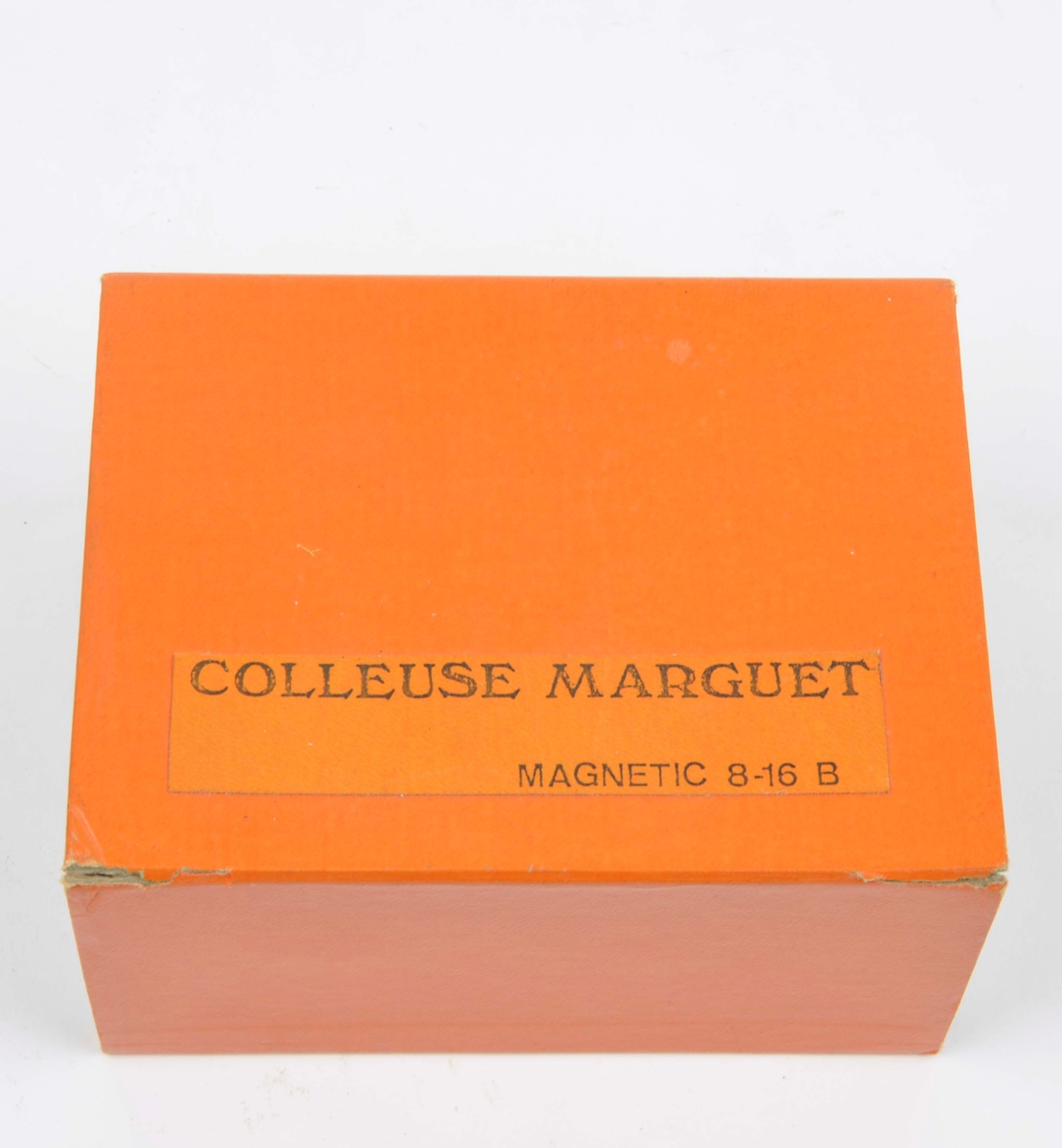Filmsax av märket Marguet Magnetic 8-16 B. Filmsaxen ligger i sin tillhörande ask som är orange och har inskriften Colleuse Marguet Magnetic 8-16 B.
