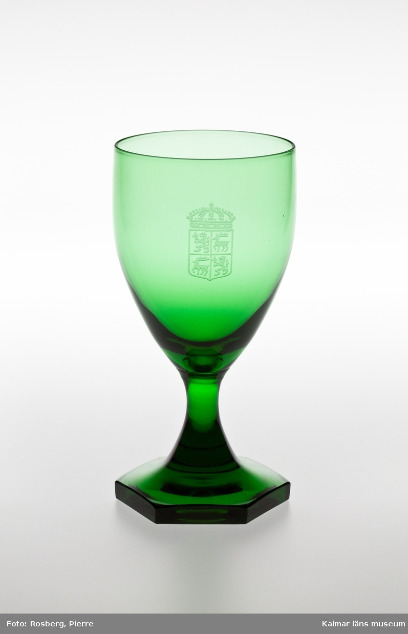 KLM 44717:14 Vittvinsglas, av glas, grönt. Kupan är graverad med vapnet för Kalmar län. Glaset är tillverkat av Orrefors glasbruk.