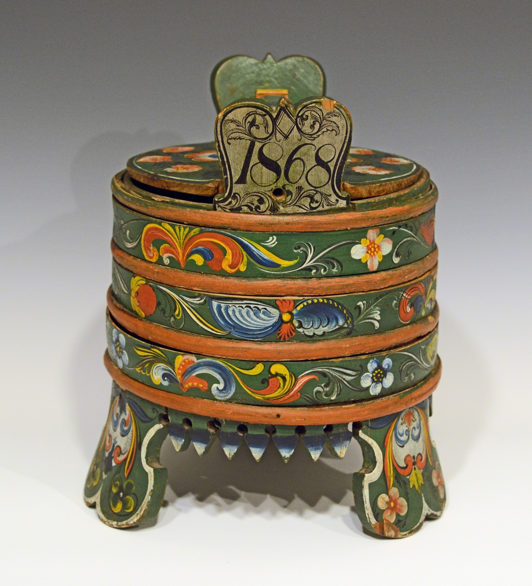 Fra protokollen:
Grøtbøtte, rosemalt av Kittel Østerholt, Lunde. Merket ATD 1868.

Grautspann med lokk. Grautspannet er lagget. Innvendig umalt, utvendig rosemalt. Det er 3 stk brede føtter og tagger i i mellom.