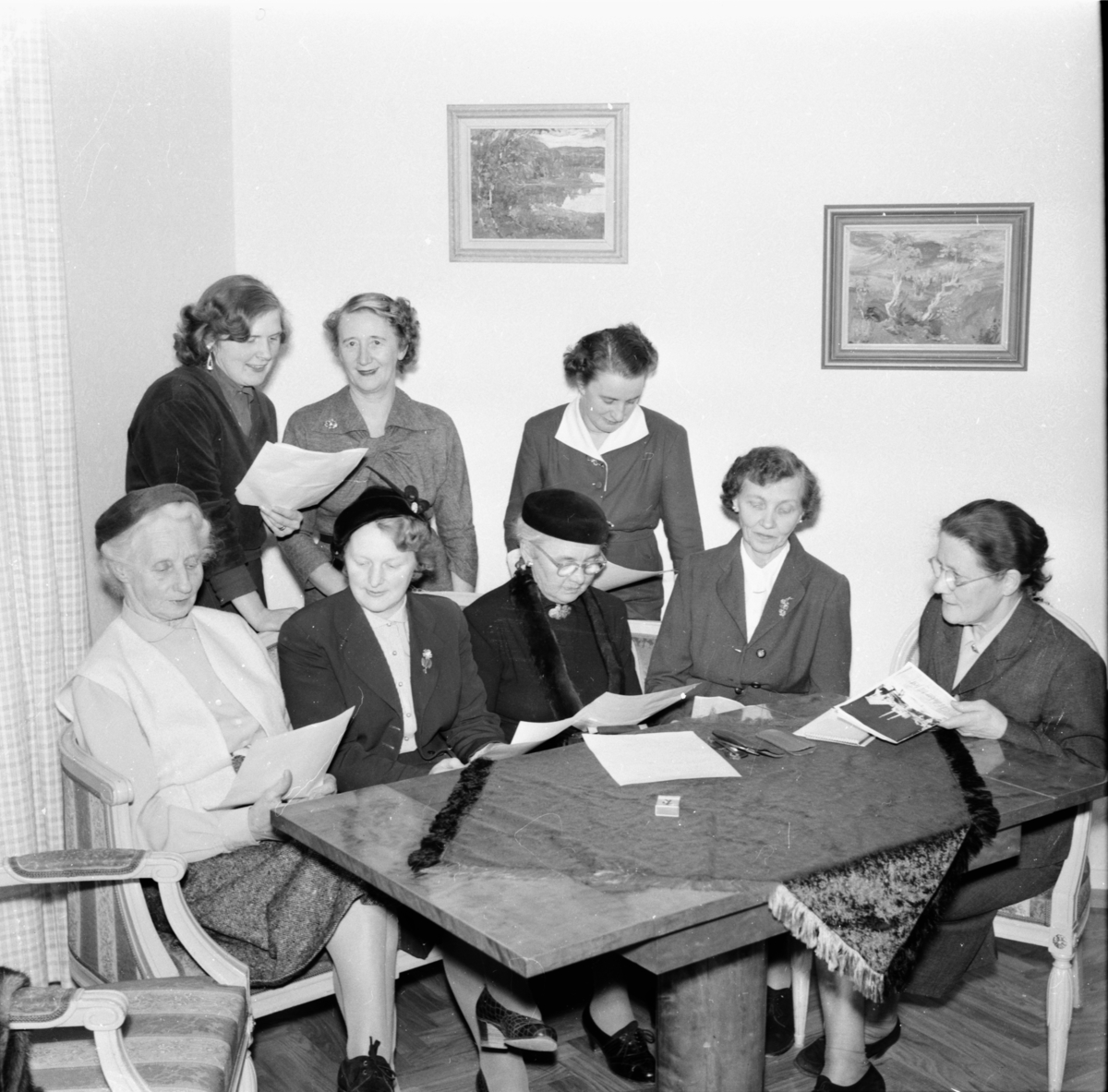Damer kring ett bord.
Till vänster Fru (Oscar) Björkman, sittande längst till höger fru Lisa Jonsson Fjäle,stående Gunnel Jonäng och längst till höger fru (boktryckare) Carlsson.