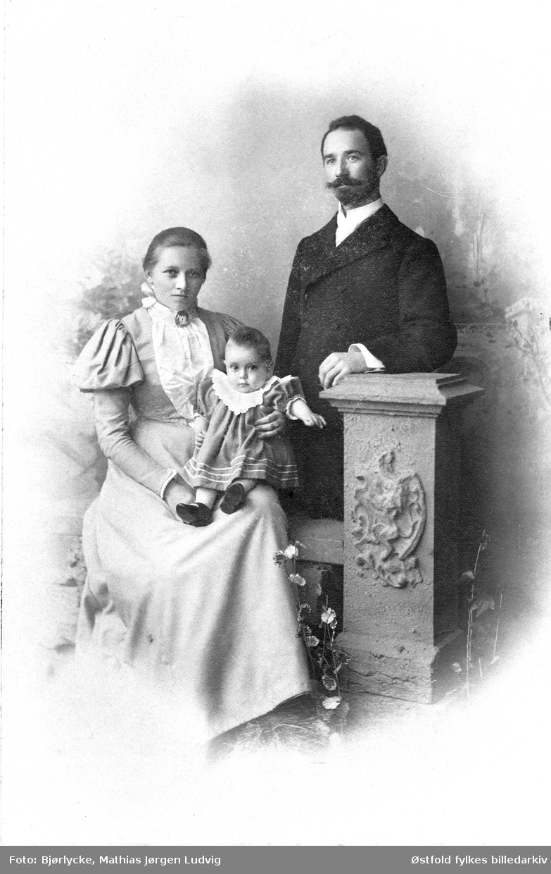 Portrett i kabinettformat tatt i atelier av ukjent kvinne og mann med barn, ca. 1897- 1902.
